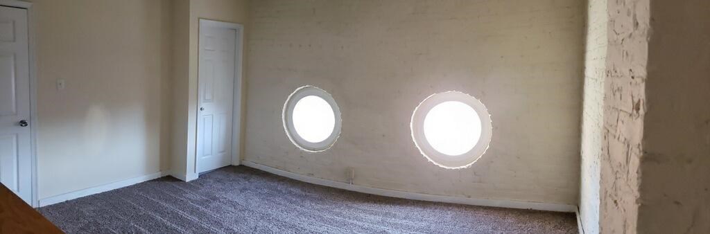 two round windows in a white room with a door